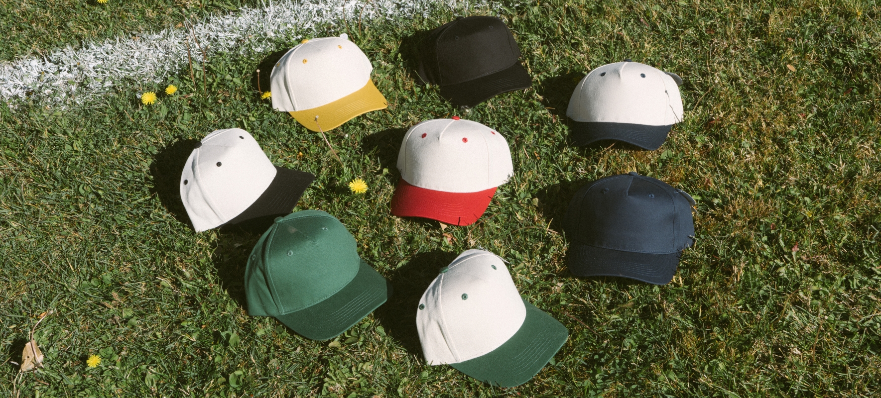 Assorted SNAG Collective snapback caps arranged on grass, showcasing custom colorways, vintage style, and premium materials