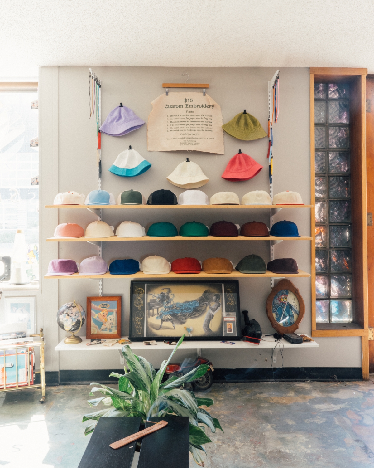 Shelves of bucket hats and caps with custom embroidery options, reflecting SNAG Collective’s small-batch, creative headwear